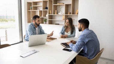Konferans masasında oturan üç profesyonel, bütçe tahsisi ve kaynakların planlanması, iş stratejilerinin paylaşımı ve takım sorumlulukları için bir araya geldiler. Çalışma Akışı