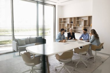 Modern konferans odasında dört takım arkadaşı, patron ve şirket müşterileri resmi toplantıya veya müzakerelere katılır, stratejiyi paylaşır, gelecekteki işbirliğini planlar, başarılı ve verimli takım çalışmalarına girişir.