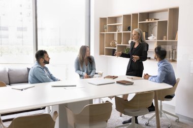 Çalışanlar için 55 'lik kadın baş antrenör, sunumunu dikkatle dinliyor, beceri geliştirme veya takım işbirliğiyle ilgili stratejiyi açıklayan eğitmen, konferans odasında bir araya geldi.