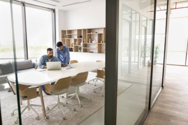 İki genç çok ırklı işadamı birlikte veri analizi yaparak dizüstü bilgisayar kullanıyor, borsa, çevrimiçi dijital platform ve iş araçları aracılığıyla eğilimleri gözden geçiriyor. Proje yönetimi yazılımı, teknoloji kullanan takım çalışması