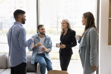 Dört profesyonelden oluşan bir grup ofis ortamında kahve molası veriyor, işyeri lobisinde bardakları tutuyor, işle ilgili arkadaşça veya gayri resmi bir sohbete girişiyor. Takım birleşmesi, etkileşim
