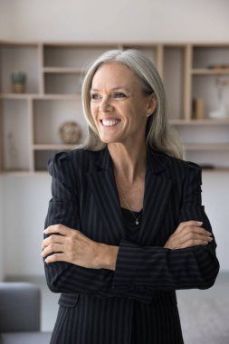 Profesyonel iş kadını, şirket patronu ya da kurucu portresi. İş yerinde duran orta yaşlı bir iş kadını iyimser bir gülümsemeyle pencereden dışarı bakar, gelecekteki başarıları ve kariyer büyümesini hayal eder.