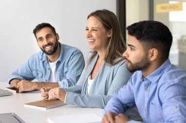 Mutlu takım arkadaşları işle ilgili konuları tartışıyor. Şirket personeli konferans masasında toplandı, sohbet ediyorlar, beyin fırtınası yapıyorlar, fikir ve çözümleri paylaşıyorlar, proje üzerinde görüşüyorlar.