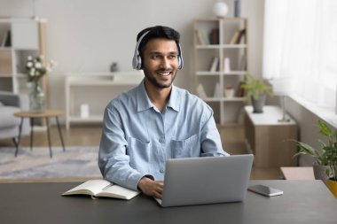 Modern teknoloji cihazları, kablosuz kulaklıklar kullanan güler yüzlü, kendine güvenen bir milenyum adamı başarılı iş iletişimi için akıllı telefon ev ofisinden eğitim almak için uzaktan kumandalı telefon.