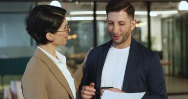 Görev arasında belgenin içeriğini tartışan iki takım arkadaşı, elinde tuttuğu kadın kupası, meslektaşlarına önemli ayrıntıları açıklıyor, gülümsüyor, başarılı sonuçlar, gelir, yardım alıyor