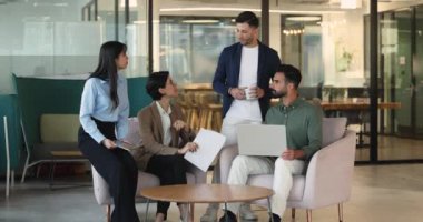 Modern çalışma sahasında ortak grup toplantısına katılan dört çok ırklı iş arkadaşı, tartışma, sunum verileri veya proje güncellemeleri, konuşma, içgörü sağlama veya planlama stratejisi