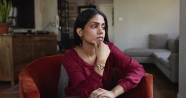 Kadın üzgün bir ifadeyle koltukta oturuyor, bunalmış görünüyor, kişisel endişeleriyle uğraşıyor, duygusal olarak yüklenmiş hissediyor, onu rahatsız eden kararları yansıtıyor. Duygusal zorluklar, yorgunluk, ayrılık.