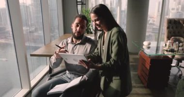 İki farklı proje çalışanı birlikte tabletten online içeriği izliyorlar, proje için internet pazarlama stratejisini tartışıyorlar, beyin fırtınası yapıyorlar, gülüyorlar, eğleniyorlar, takım çalışmasından keyif alıyorlar.