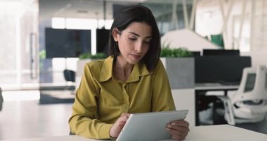 Modern ofis masasında oturan, dijital tablete odaklanan, haberleri okuyan ya da bilgiyi analiz eden, yeni iş uygulamalarını gözden geçiren, yenilikçi yapay zeka platformunu öğrenen 30 'lu yaşlardaki genç profesyonel Brezilyalı kadın.