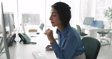 30 'lu yaşlarda profesyonel bir kadın, modern ofiste masa başında çalışan, bilgisayar monitörüne odaklanmış, iş e-postalarını okuyan, verileri analiz eden, belgeleri inceleyen, ya da belgeleri düzenleyen