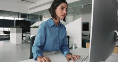 Çağdaş çalışma alanında bilgisayar üzerinde çalışan odaklanmış Latin kadın, mesleki veya analitik görevleri tamamlama, raporları gözden geçirme veya mali verileri gözden geçirme, belge hazırlama veya düzenleme