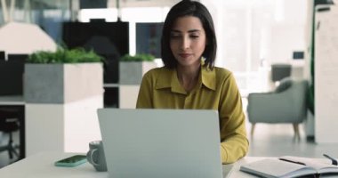 Mutlu Latin kadın ofis çalışanı dizüstü bilgisayarda işi başardı. Yakın cihaz tebessümü, neşeli bir ifadeyle sandalyeye yaslandı, tatilin tadını çıkardı, görevi tamamlamaktan memnun kaldı, verimli bir çalışma gününü tamamladı.