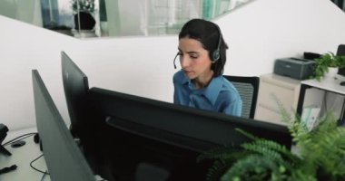 İş yerinde çalışan kulaklık takan genç Brezilyalı kadın bilgisayar başında oturuyor, müşteri desteği, teknik yardım, telekomünikasyon hizmetleri veya satışla ilgili bir konumda yer alıyor.