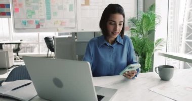 Modern iş yerinde dizüstü bilgisayar ve akıllı telefon kullanan odaklanmış ofis çalışanı, e-postalara yanıt veriyor, iki kablosuz aygıt arasındaki bilgileri senkronize ediyor, zamanlamaları güncelliyor, notları kaydediyor veya dosya aktarıyor