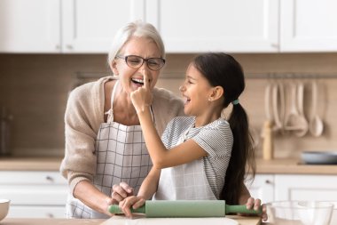 Küçük, oyuncu bir ergen kız mutfakta şaka yapıyor ve gülüyor. Büyükannenin burnuna un işareti koyuyor. Yaramaz çocuk, yaşlı büyükanneye yardım ediyor, eğleniyor, yemek yapıyor, oyun oynuyor.