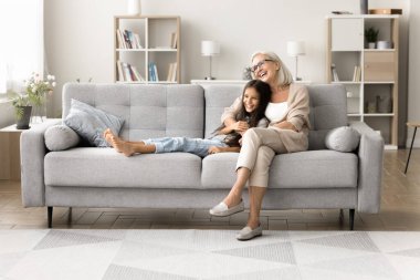 Sevecen, yaşlı bir büyükanne büyük rahat bir kanepede sevgili küçük torununa sarılıyor. Sevgi dolu büyükanne, tatlı torun kızıyla sıcak bir evde tanışmaktan zevk alıyor. Hafta sonları çocukla vakit geçiriyor.