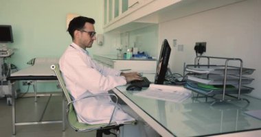 Ciddi ultrason teşhisi bilgisayarda tıbbi kayıtlar üzerinde çalışan, belgeleri okuyan, klavyede yazan, monitörü gösteren, sınav sonuçlarını düşünen, çeneye dokunan