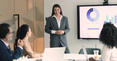 Pozitif genç proje yöneticisi kadın satış raporunu sunuyor, pazarlama stratejisi verilerini çeşitli meslektaşlara sunuyor. İşletme koçu şirket çalışanlarına eğitim semineri veriyor.