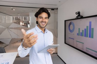 Tabletli genç İspanyol iş adamı kameraya davetiye çıkarıyor, müşterileri, ortakları, iş adaylarını ağırlıyor, takıma katılmaya davet ediyor, portre için poz veriyor.