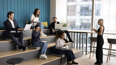 Yetişkin bir işletme koçu ya da eğitmeni tarafından yönetilen profesyonel toplantı ya da atölye. Çok ırklı bir grup öğrenci ve şirket personeli, patronun düzenlediği eğitim brifingine, seminer etkinliğine katılıyor.