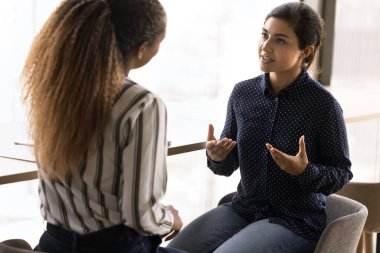 İki çok ırklı kadın, ortak iş konuları, iş stratejileri, proje güncellemeleri veya sorun çözme konularını tartışarak ofiste buluştu. Takım çalışması, fikir alışverişi, iletişim.
