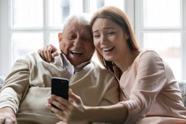 Aşırı mutlu yaşlı 80 'lerin baba ve yetişkin kızı evde rahatlayıp hücrede kendi portreni yaparken, mutlu yaşlı baba ve yetişkin çocuk gülümsemesi ile evde akıllı telefondan selfie çekerken eğlenin.