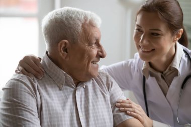 Olumlu kadın hemşire sarılma konuşması ve yaşlı 80 'lerin erkek hastalarını desteklemek, gülümseyen kadın doktor ya da bakıcı yetişkin erkek müşterilerle ilgilenmek, yaşlı sağlık hizmetleri kavramı