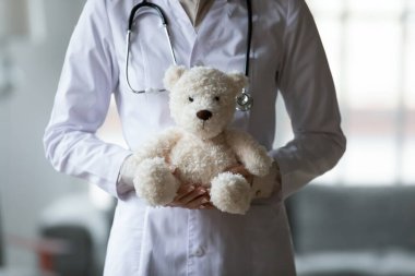 Beyaz üniformalı kadın hemşire ya da pratisyen hekime yakın durun doldurulmuş oyuncaklar, küçük hastalar, poz veren çocuk doktoru poz veren oyuncak ayıcıklar, hastane veya özel klinikte bekleyin.