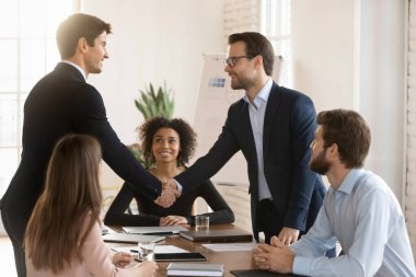 İki başarılı yönetici resmi ceketli adamlar takım toplantısında birbirlerini selamlıyor, işbirliği, takım çalışması, iş anlaşması, anlaşma ve anlaşmadan sonra ortaklaşa tokalaşıyorlar.