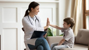 Beyaz üniformalı gülümseyen kadın doktor, küçük hasta, arkadaş canlısı çocuk doktoru, pratisyen hekime beşlik çakıyor. Klinikte anaokulu öğrencisini selamlıyor, iyi sağlık kontrolü sonuçlarını kutluyor.