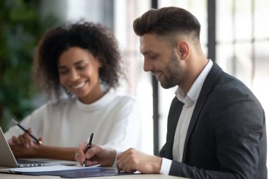 Mutlu Kafkasyalı genç erkek başvuru sahibi başarılı bir iş görüşmesi sonrasında kağıt sözleşmesi imzaladı, gülümseyen iş ortağı müvekkili belgeye imza attı, anlaşma yaptı, iş buldu.