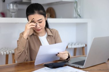 Endişeli genç Asyalı muhasebeci kadın kötü haberlerle yasal mali belge alıyor, bütçe aşımını, para kaybını, laptopun kapalı gözleriyle kafaya dokunmayı buluyor.