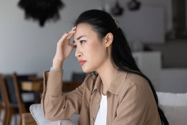 Depresyondaki genç Asyalı kadın kötü sağlık sorunları, sorunlar, dokunmak, başka yere bakmak, baş ağrısı, bitkinlik, depresyona girmek gibi şeyler düşünüyor.