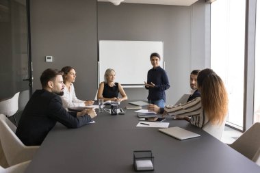 Modern konferans odasında iletişim kuran, liderlik eden, potansiyel çözümler veya strateji öneren profesyonel iş ekibi, önemli verileri vurgulayan resmi toplantıya veya seminer etkinliğine katılır.