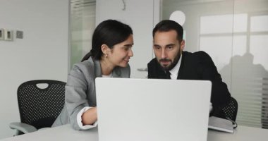 Dost canlısı İspanyol ve Lübnanlı meslektaşlar modern dizüstü bilgisayarla ortak bir iş üzerinde çalışıyorlar, iş yerinde mola sırasında içeriği izlerken gülüyorlar, ortak projenin sonuçlarını gözden geçiriyorlar tatmin oluyorlar.