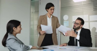 İş adamları toplantı odasında toplanan seminerlere veya brifinglere katılıyor. Dosyaları ve grafikleri meslektaşlarına dağıtan, sunulan bilgileri inceleyen, karar veren, plan yapan bir kadın.