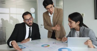 Masaya yayılmış grafikler ve grafikler etrafında tartışan meslektaşlar. Üretken beyin fırtınası oturumu, strateji toplantısı karar verme verilerinin analiz edilmesi ve yorumlanması üzerine odaklandı