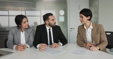 Resmi giyinmiş iş ortakları konferans masasında oturuyorlar, sözleşme imzalıyorlar, belgelere imza atıyorlar, el sıkışıyorlar saygılarını sunuyorlar, kârlı ticari anlaşmaları kapatıyorlar, tatmin oluyorlar.