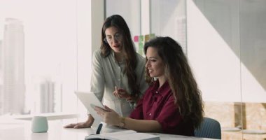 Kadınlar tablette gösterilen içerik veya bilgileri tartışır, sunumu inceler, proje detaylarını analiz eder, planlama stratejisini analiz eder, tasarım, keşif araçları ve çalışmalarıyla ilgili yaratıcı fikirleri paylaşırlar.