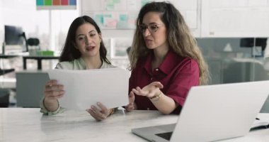 İş birliği yapan kadın meslektaşlar, bir yığın belge tutarlar, belirli ayrıntılara dikkat çekerler, yeni bilgileri açıklar, açıklar, analiz eder, müvekkille görüşmeden önce sözleşme şartlarını gözden geçirirler.