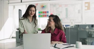 Avrupalı kadın iş arkadaşları ofiste konuşurken dizüstü bilgisayara bakın, yeni yapay zeka programını gözden geçirin, proje üzerinde çalışın, strateji geliştirin, tatmin olun ve başarılı, üretken iş akışından ve portreden memnun olun