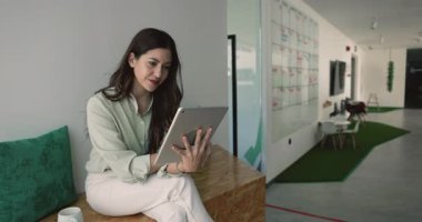Odaklanmış Latin iş kadını, serbest çalışan, rahat bir ofiste dijital tablet kullanan şirket çalışanı, bulut platformları kullanarak belgeler üzerinde çalışan, notlar alan ya da fikir üretme uygulaması kullanan