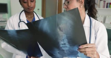 İki doktor klinikte yapılan toplantıda röntgen incelemesi, görüntüleme, MRI sonuçlarını gözden geçirme, kırık veya yaralanma tedavisini paylaşma, daha ileri teşhis testleri planlama, görüş ve beceri alışverişi