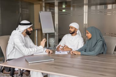 Geleneksel Müslüman kıyafeti giymiş genç Arap çift iş dünyasının ticari tekliflerini dinliyorlar, konuşma yapıyorlar, ofiste eşlerine danışıyorlar. Hizmetler, tartışma, ortaklık