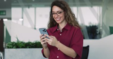 Çekici Avrupalı kadın, elinde modern akıllı telefon tutan ofis çalışanı, baş resmi, kişisel sohbet, daktilo mesajları, set hatırlatıcıları veya iş yerindeki yeni mobil iş yapay zeka platformu veya uygulamaları kullanarak