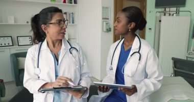 Hasta tıbbi geçmişini inceleyen iki genç ve olgun kadın doktor, son test sonuçlarını tartışıyor, teşhis ve tedavi planlarını tartışıyor, başarılı ve etkili takım çalışmasına saygı gösteriyor