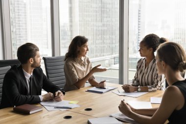 Çok ırklı iş adamlarından oluşan bir grup yüksek katlı ofisteki konferans odasında toplandı, stratejilerini tartıştılar, şirket faaliyetlerini optimize etme, kilit güçlükleri gözden geçirme ve arama çözümlerini gözden geçirme konusunda karar verdiler.