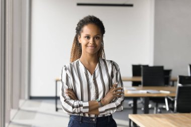 Modern ofiste kolları çapraz duran, liderlik yapan, yöneticilik pozisyonunda olan kendinden emin Afrikalı profesyonel bir kadın. Proje yöneticisi, pazarlama yöneticisi, takım lideri portresi