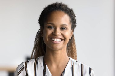 Kapalı fotograflı genç Afrikalı kadın rahat gömlekli samimi bir gülümsemesi var, kameraya bakın. Amerikalı iş kadınının profil fotoğrafı, özgüven, içeride pozitiflik.