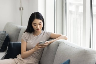 Akıllı telefonlu, internetten alışveriş yapan, e-alışveriş sitelerine göz atan, video izleyen, e-postaları kontrol eden, uygulamalarla mesajlara cevap veren Çinli bir kadın.